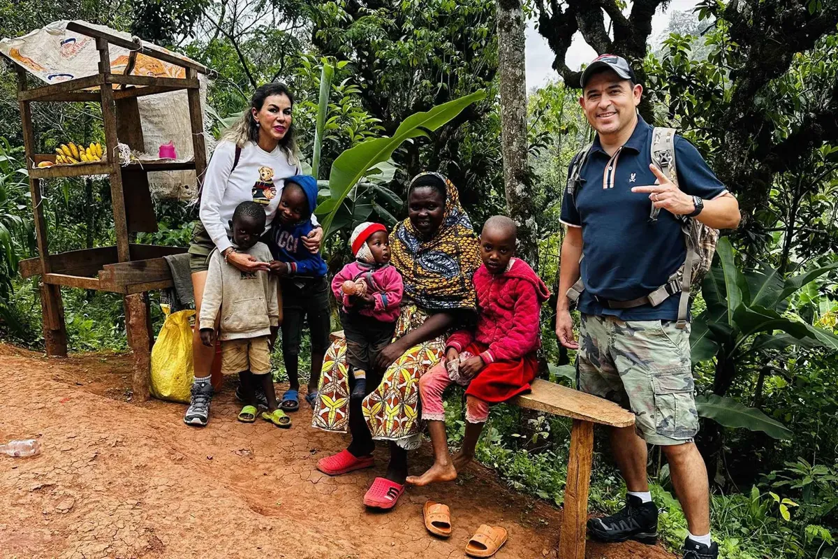 A family visiting a village near Moshi with their guide, sitting with local women and children