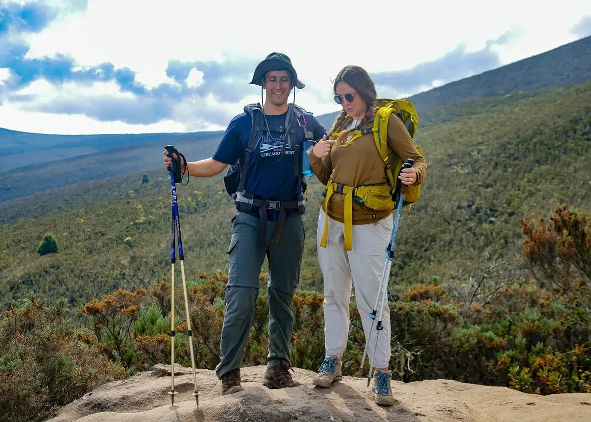 A honeymoon couple with trekking poles in Kilimanjaro's heath zone