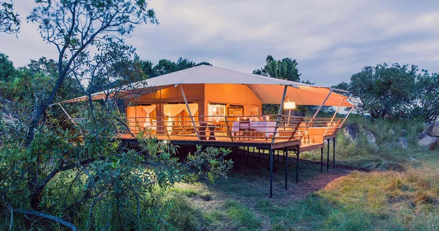 Luxury Serengeti safari camp and safari vehicle at sunset